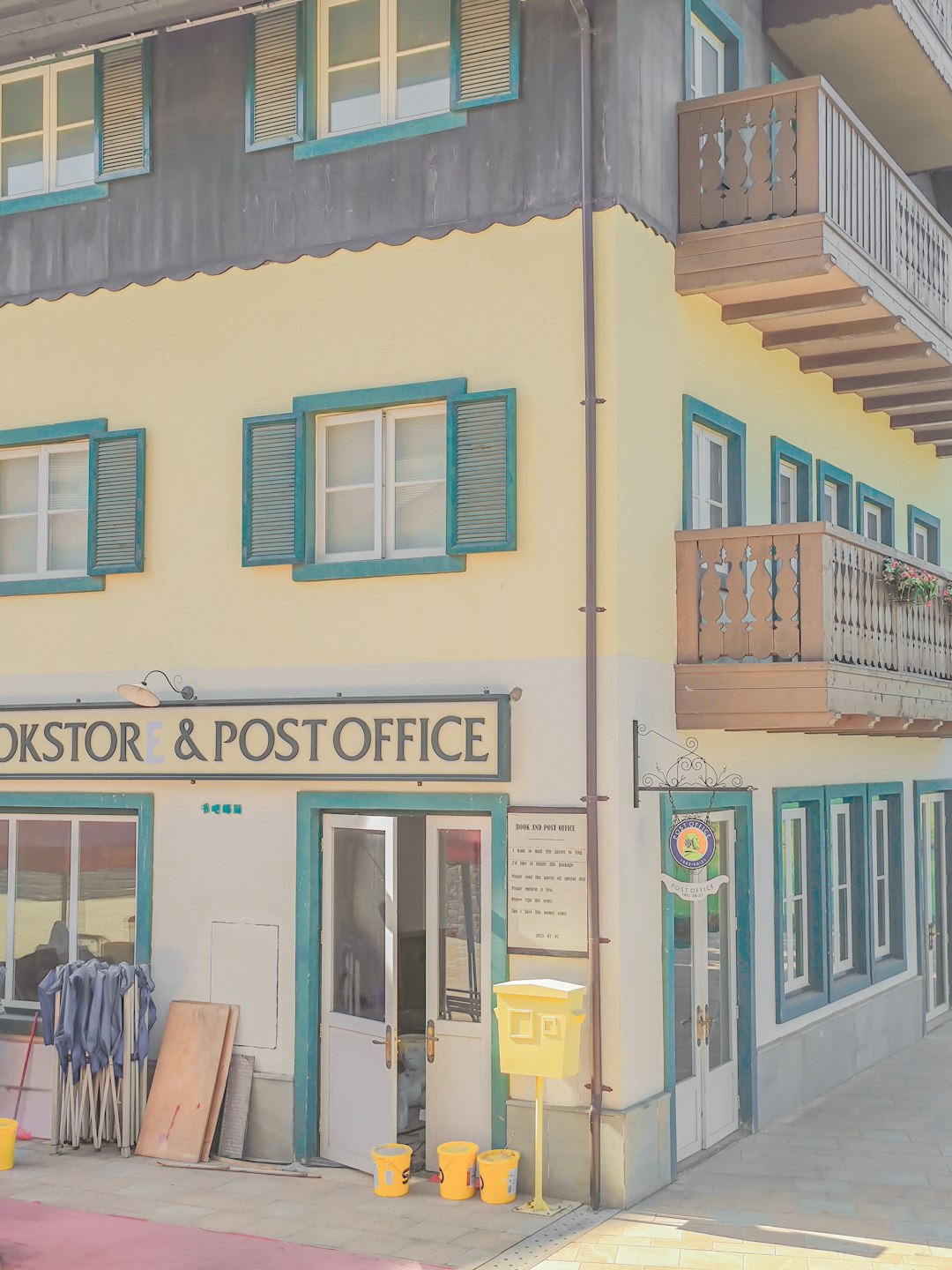 a-yellow-and-green-building-with-green-shutters-locejlpznhk